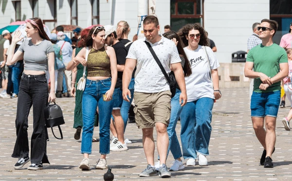 Two people walking through an urban neighbourhood street on a bright day